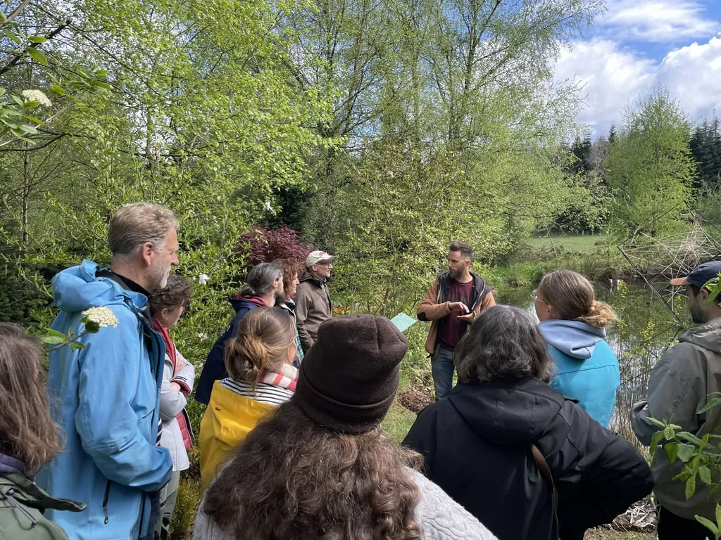 Visite guidée du jardin-forêt : groupe rassemblé près d'une mare au printemps